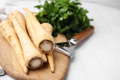 Whole raw parsley roots and fresh herb on white table, closeup. Space for text