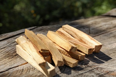 Palo santo sticks on wooden table outdoors, closeup