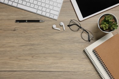 Photo of Flat lay composition with computer keyboard and different stationery on wooden desk, space for text. Home office