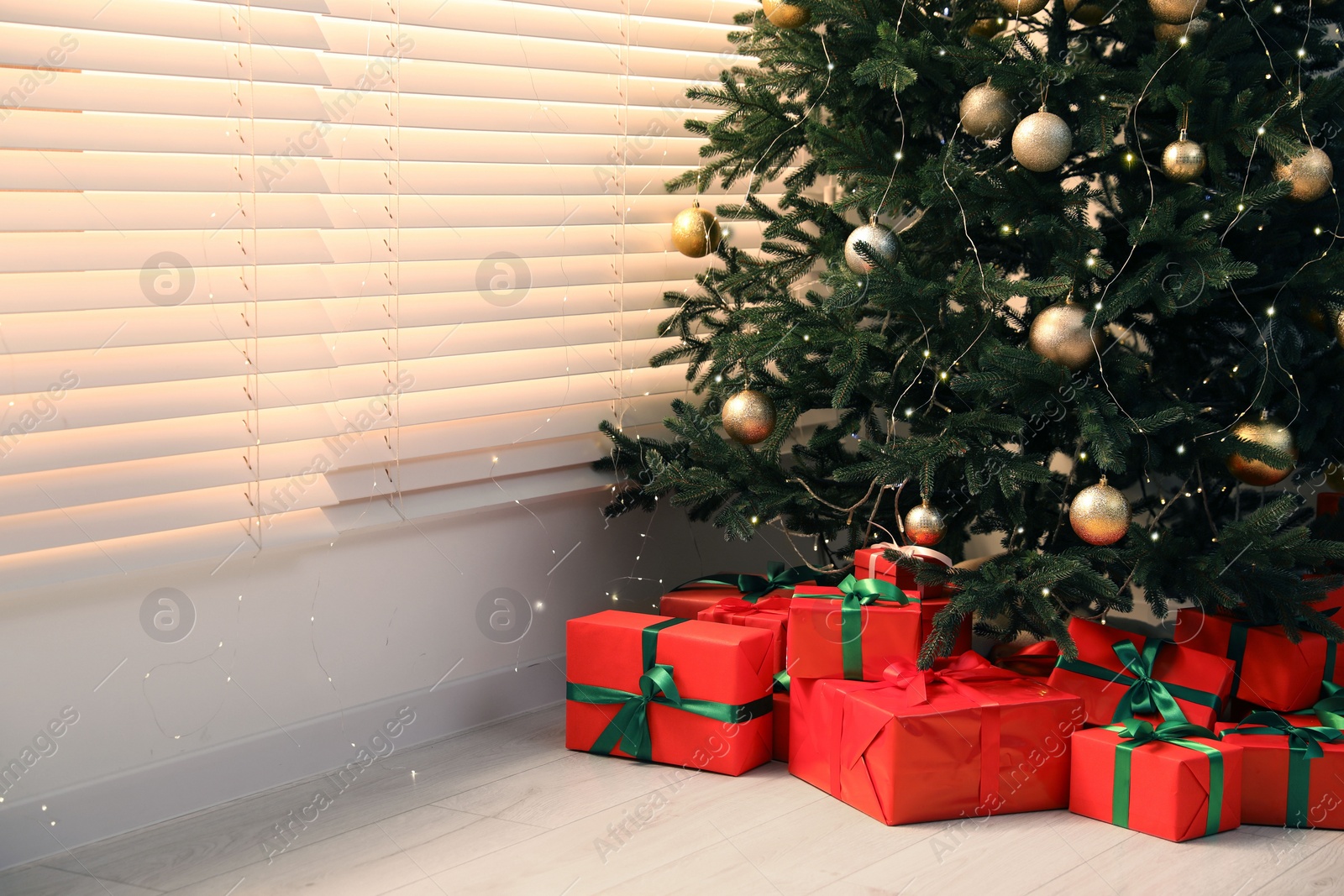 Photo of Beautifully wrapped gift boxes under Christmas tree in living room. Space for text