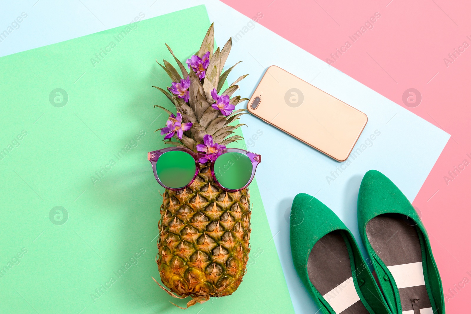 Photo of Flat lay composition with ripe pineapple, sunglasses, shoes and mobile phone on color background