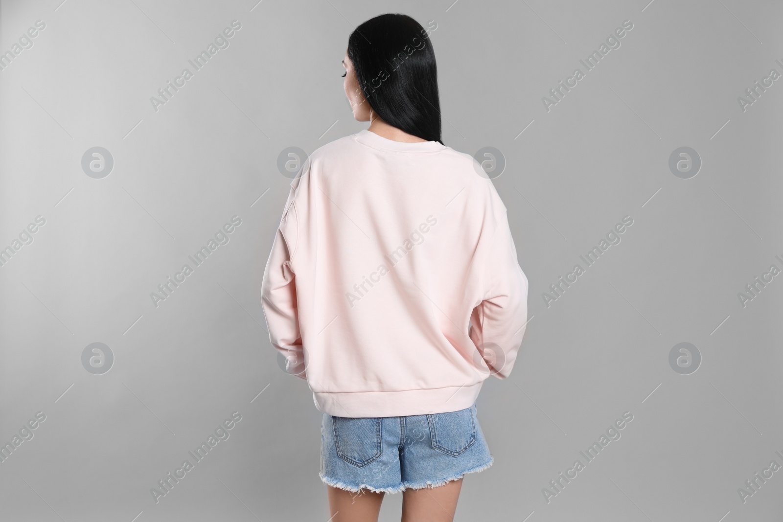 Photo of Young woman in sweater on grey background. Mock up for design