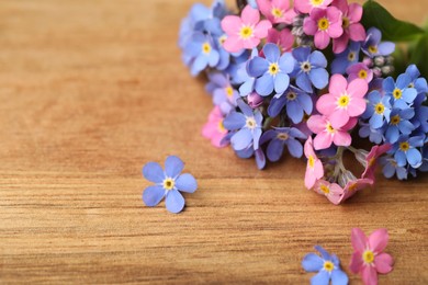 Photo of Beautiful fresh Forget-me-not flowers on wooden table, closeup. Space for text