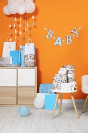 Photo of Baby shower party. Festive decor, gift boxes, booties and toy in stylish room