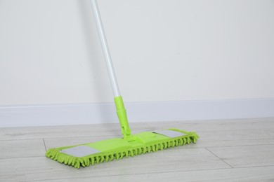 Photo of Mop with plastic handle near wall indoors. Space for text