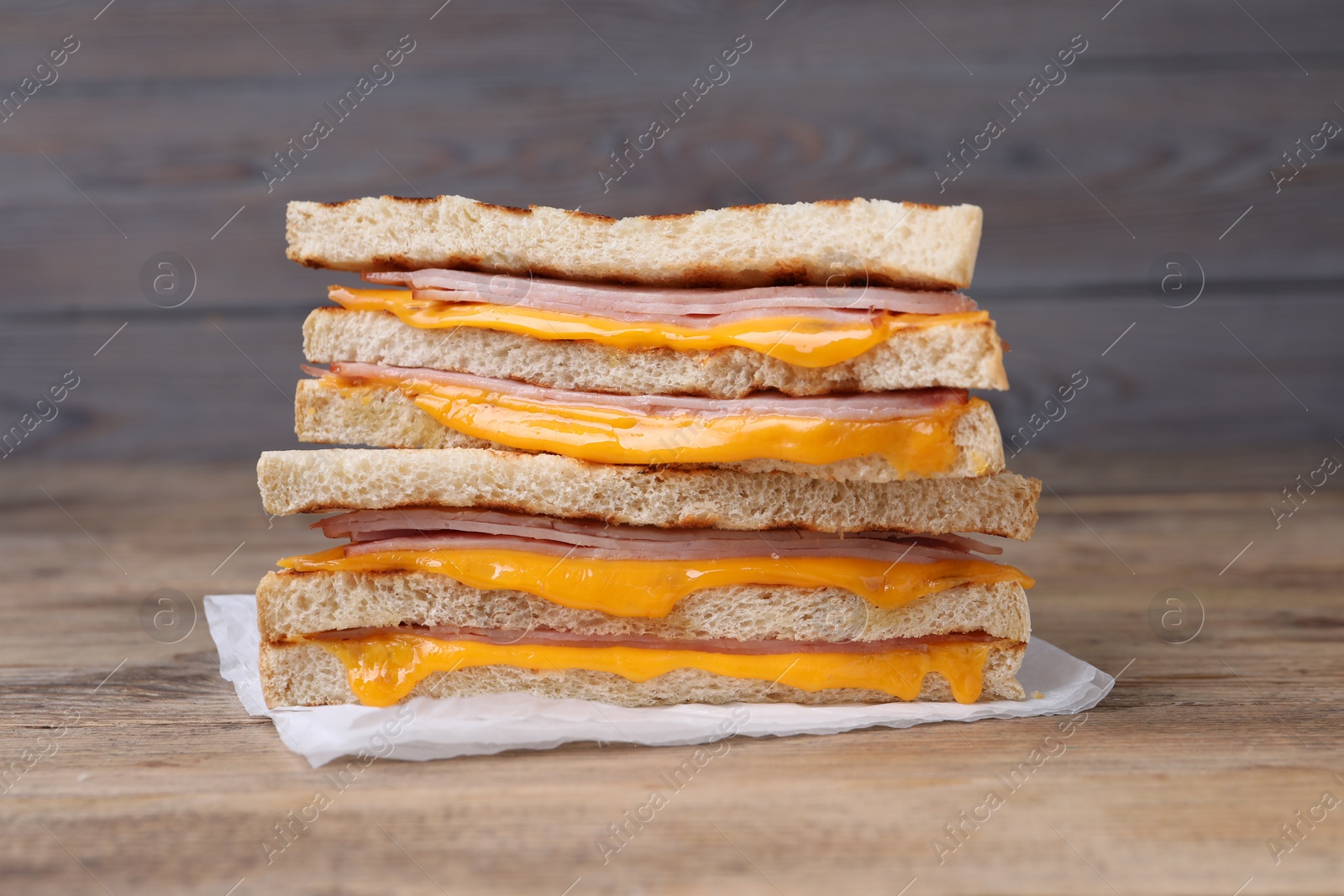 Delicious grilled sandwiches with ham and cheese on wooden table, closeup Photo of Delicious grilled sandwiches with ham and cheese on wooden table, closeup