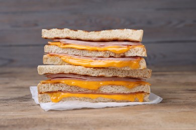 Photo of Delicious grilled sandwiches with ham and cheese on wooden table, closeup