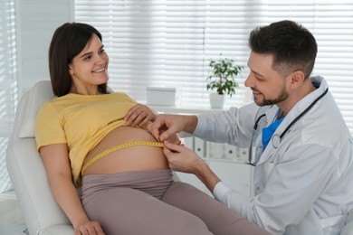 Photo of Doctor measuring pregnant woman's belly with tape in clinic