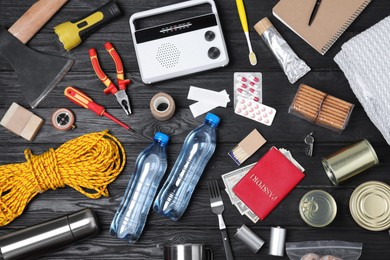 Photo of Disaster supply kit for earthquake on black wooden table, flat lay