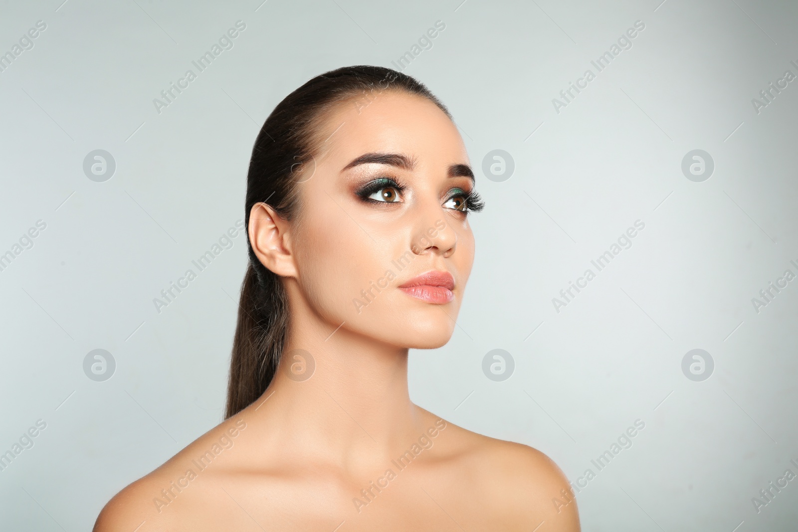 Photo of Portrait of young woman with eyelash extensions and makeup on light background. Space for text