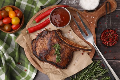 Photo of Tasty grilled meat, rosemary and marinade served on wooden table, flat lay