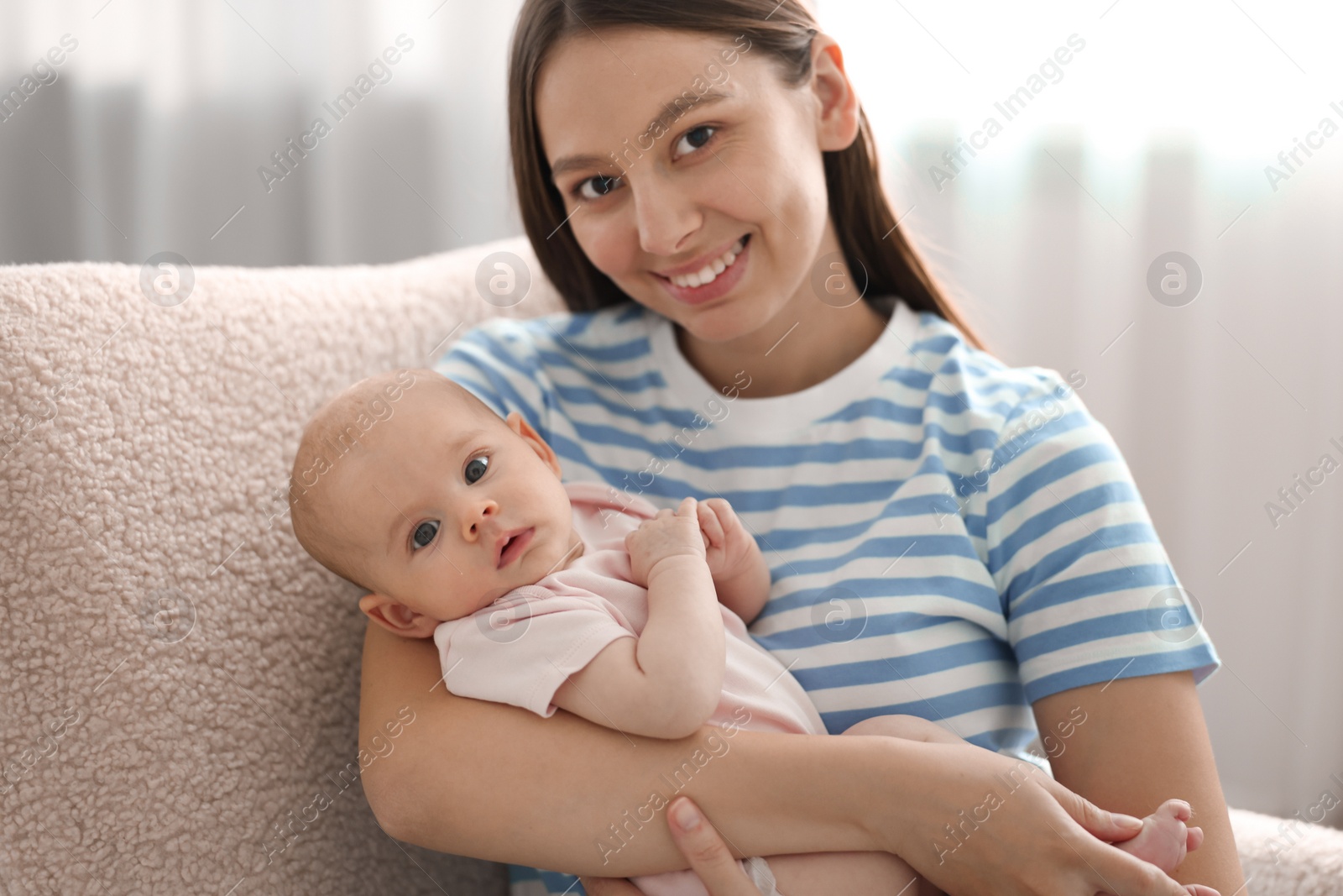 Photo of Mother with her cute baby in armchair at home