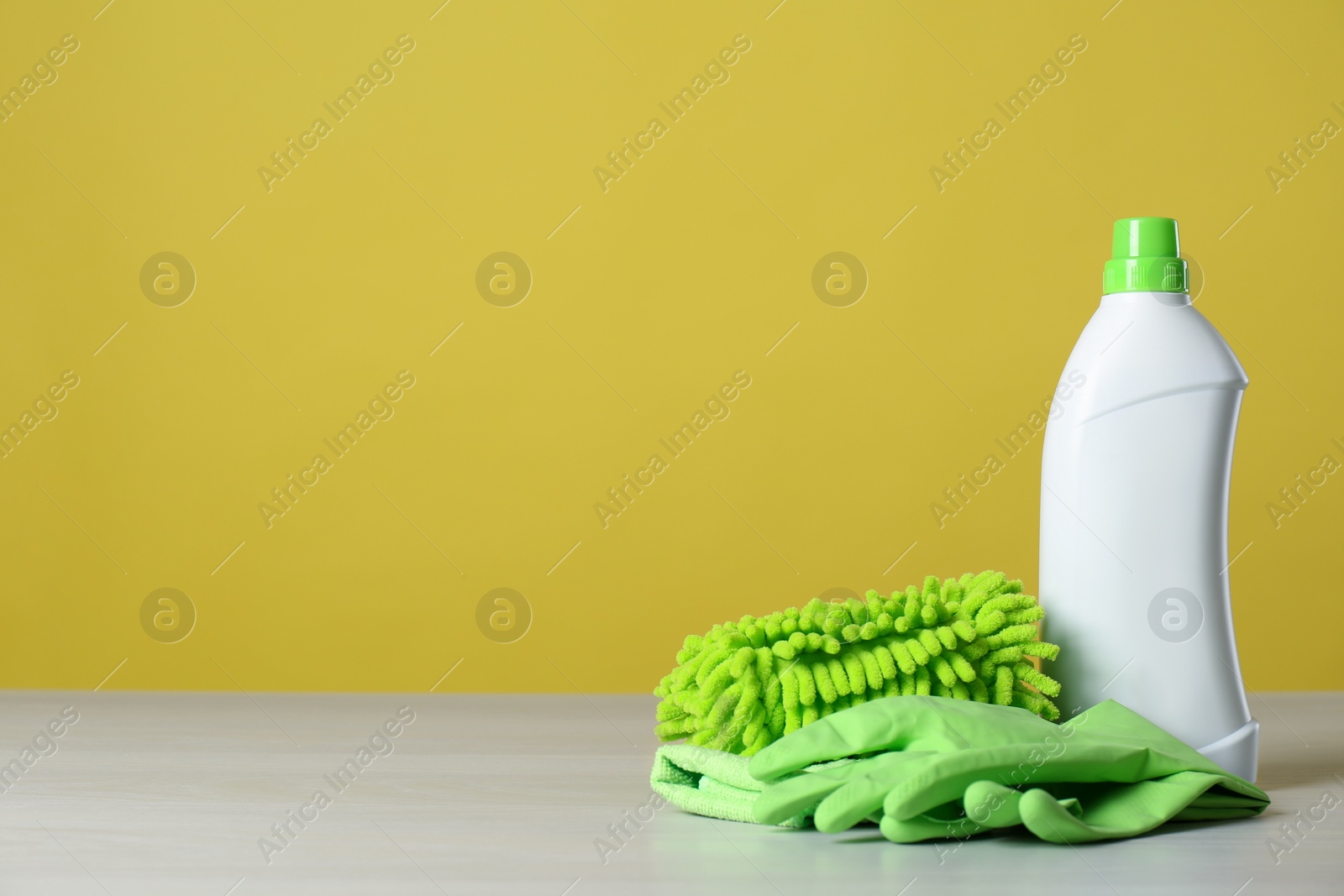 Photo of Bottle of cleaning product and supplies on light table. Space for text