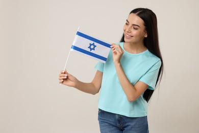 Photo of Happy young woman with flag of Israel on beige background
