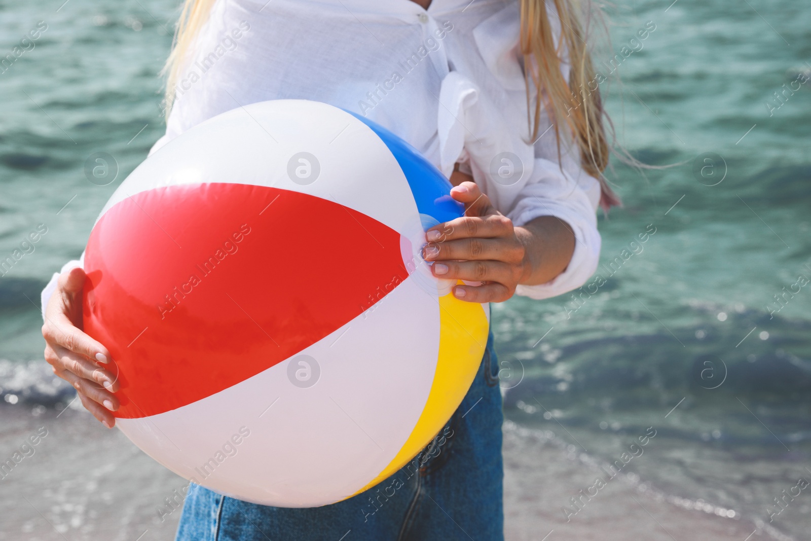 Photo of Young woman with inflatable beach ball near sea on sunny day, closeup