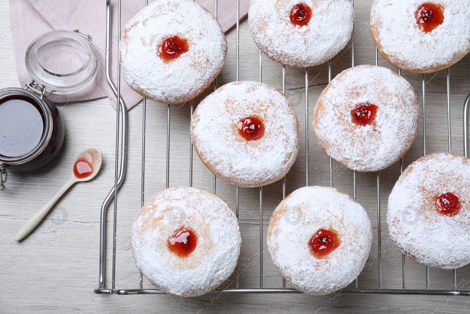 Photo of Many delicious donuts with jelly and powdered sugar on wooden table, flat lay