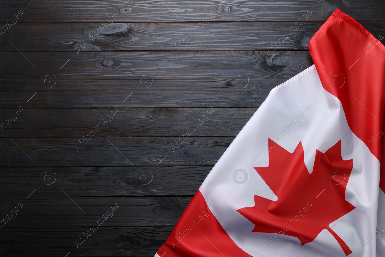 Photo of Flag of Canada on dark wooden table, top view. Space for text