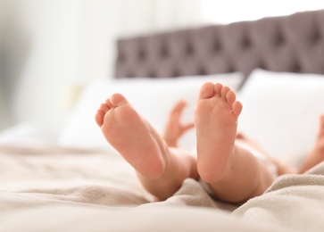 Cute little baby lying on bed, closeup of legs. Space for text