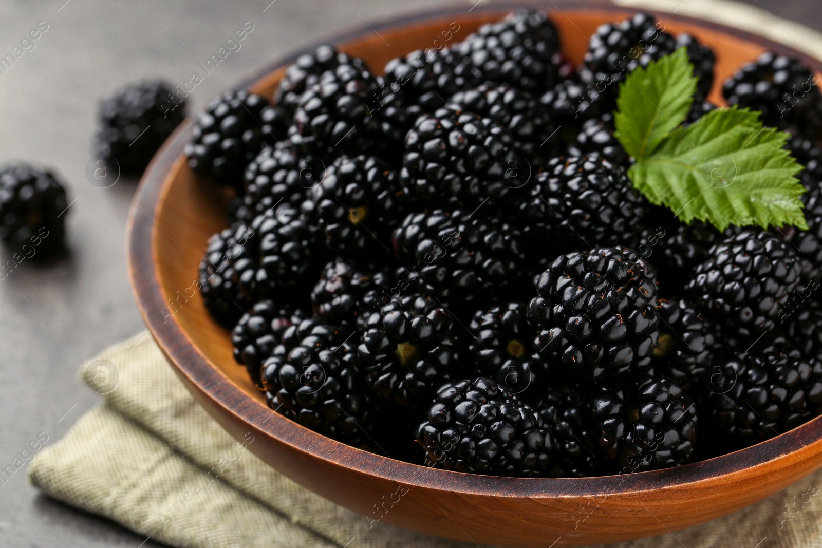 Photo of Bowl with fresh ripe blackberries on dark grey table, closeup