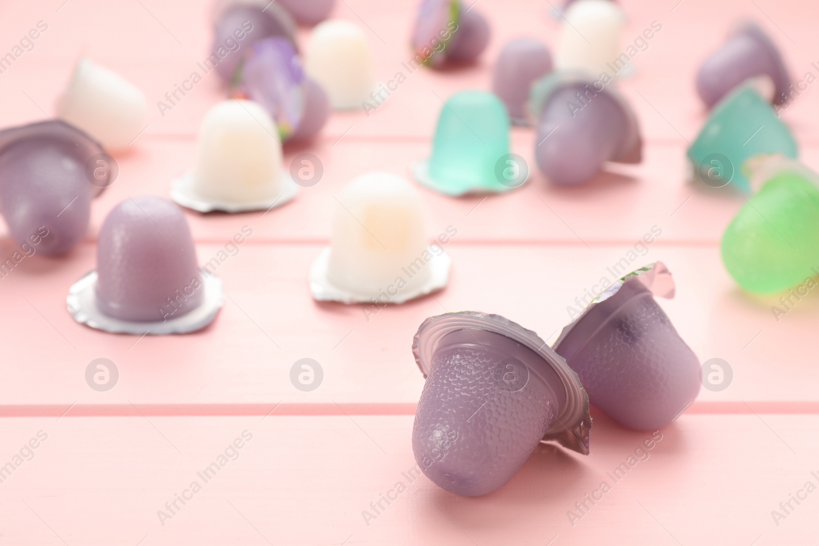 Photo of Tasty bright jelly cups on pink wooden table