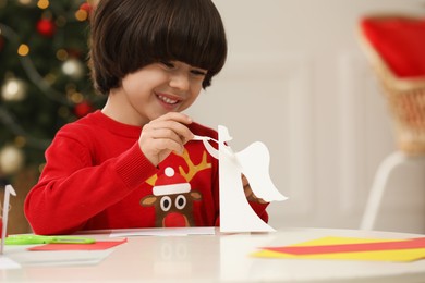 Photo of Cute little boy with paper angel for Saint Nicholas day at home
