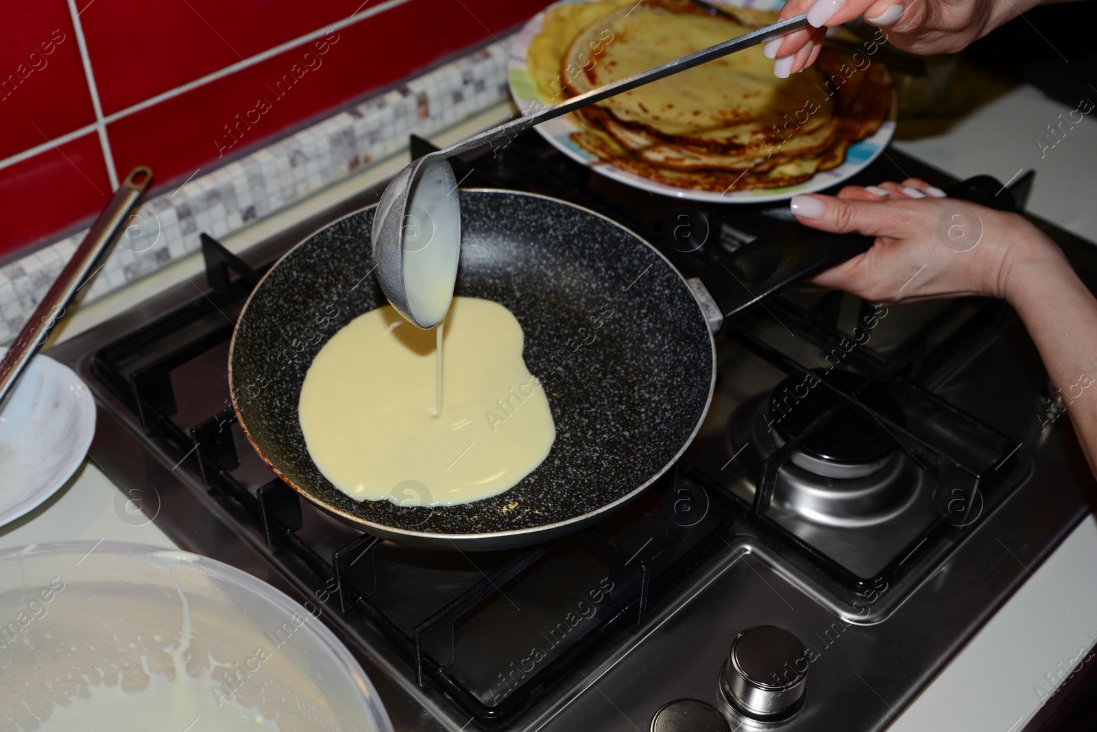 Photo of Woman pouring crepe batter onto frying pan in kitchen, closeup