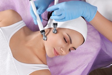 Photo of Young woman undergoing cosmetic procedure in beauty salon, top view. Microcurrent therapy