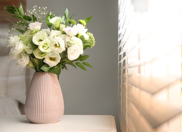 Photo of Bouquet of beautiful flowers on nightstand in bedroom, space for text. Interior design