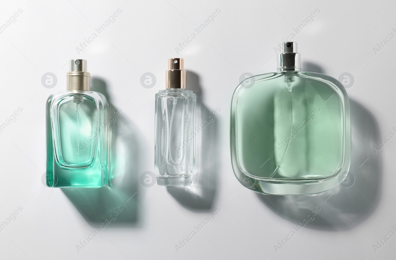 Photo of Bottles of perfume on light background, top view