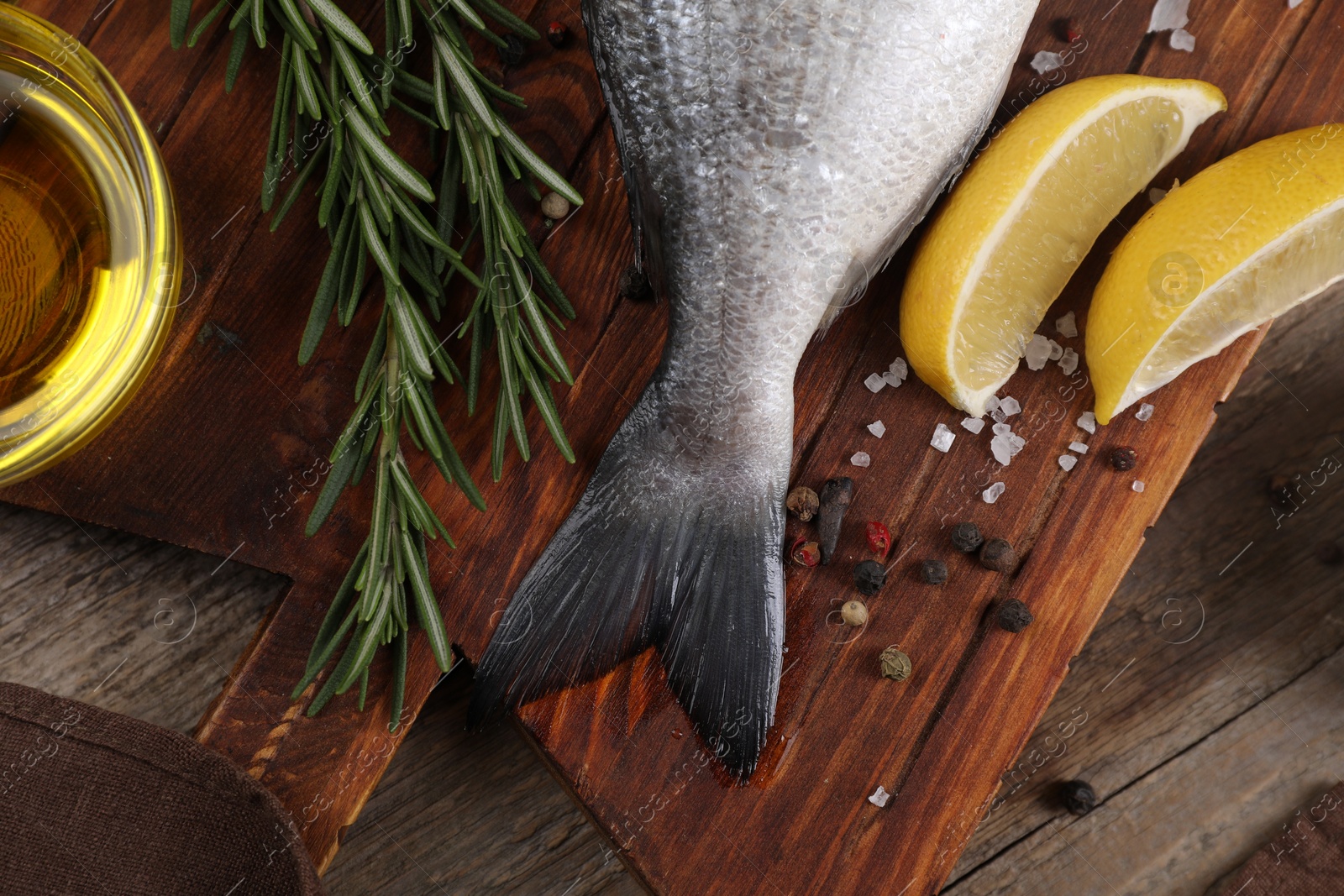 Photo of Raw dorado fish, lemon wedges and spices on wooden table, flat lay