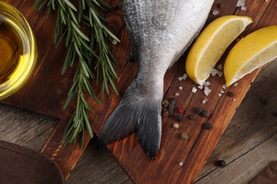 Raw dorado fish, lemon wedges and spices on wooden table, flat lay