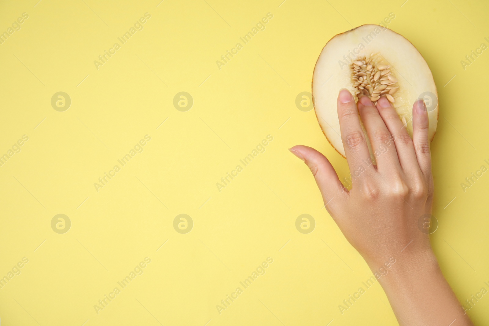 Photo of Young woman touching half of melon on yellow background, top view with space for text. Sex concept