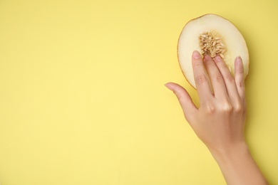 Young woman touching half of melon on yellow background, top view with space for text. Sex concept