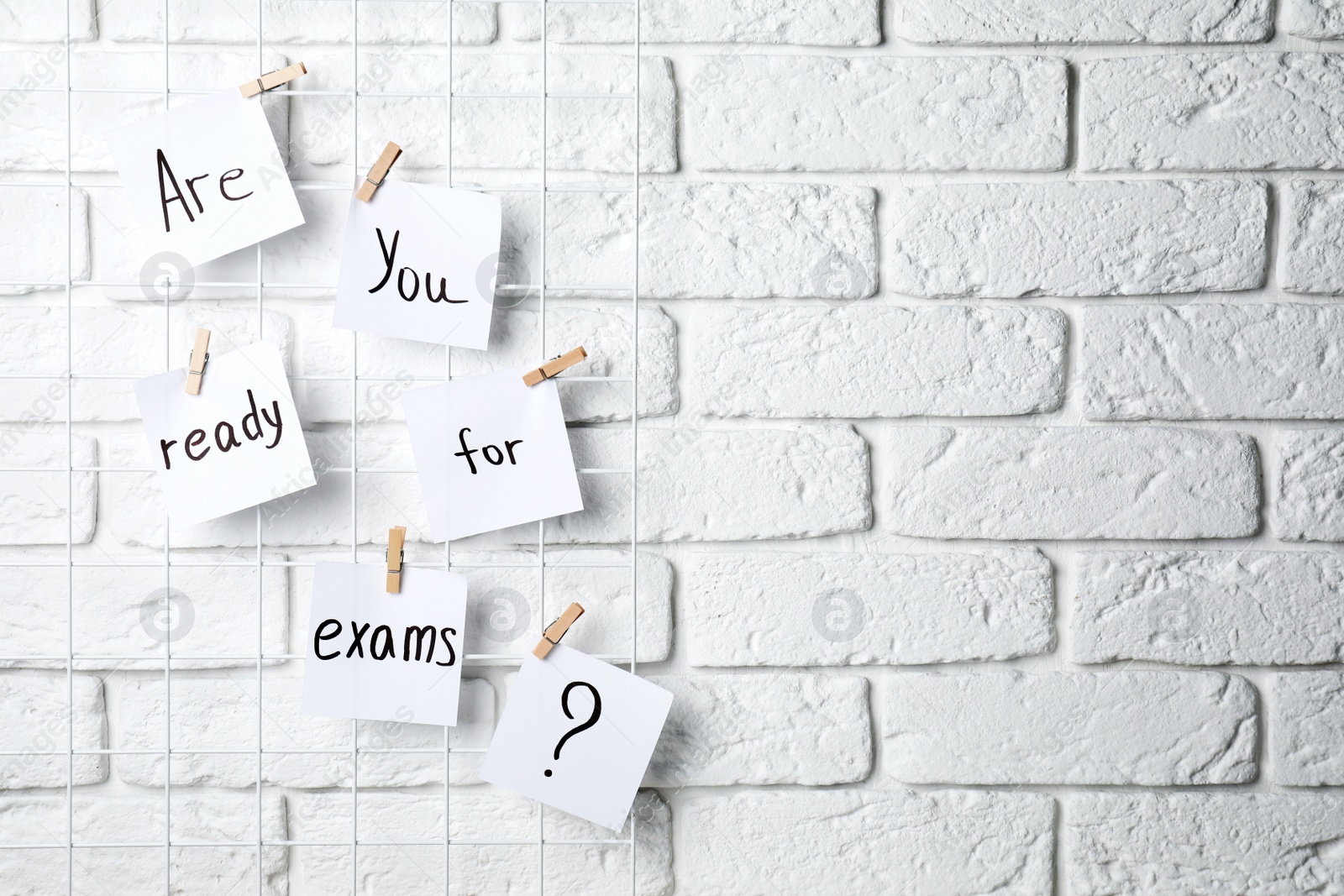 Photo of Notes with phrase Are you ready for exams hanging on white brick wall, space for text