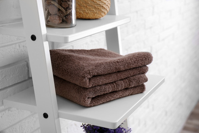Clean soft towels on shelf near white brick wall