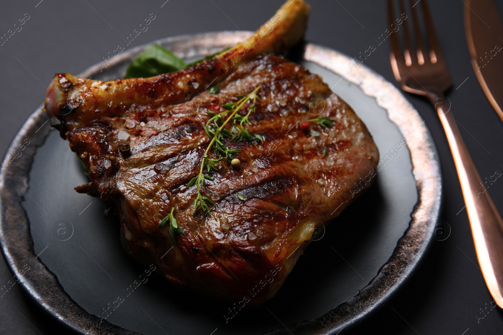 Photo of Plate with grilled meat steak on black background, closeup