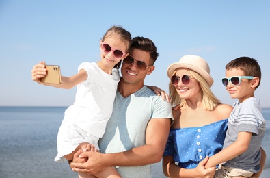 Photo of Happy family taking selfie at beach on sunny day