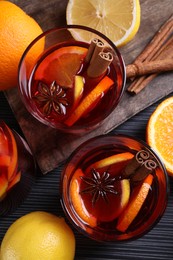 Photo of Aromatic punch drink and ingredients on black table, flat lay