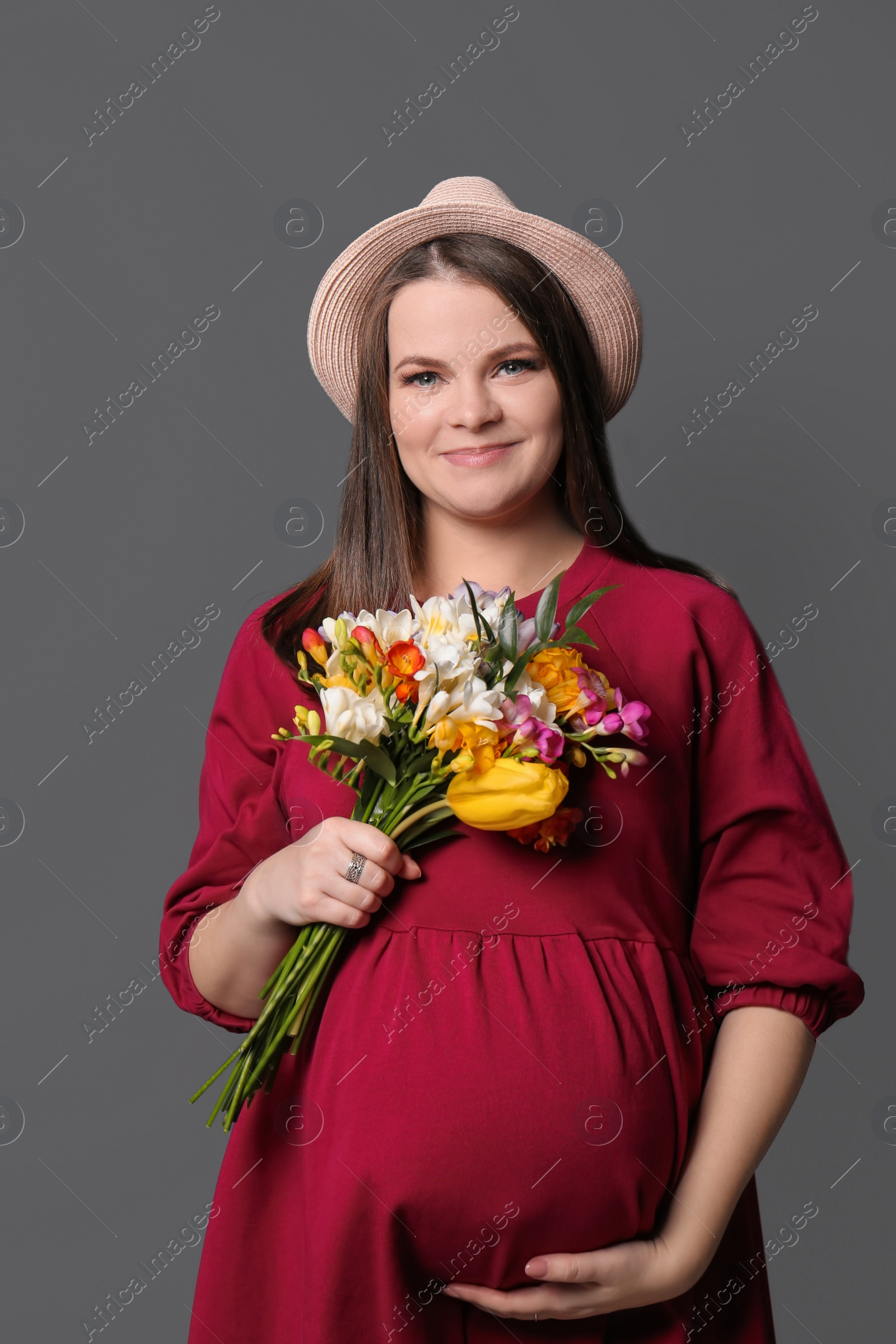 Photo of Beautiful pregnant woman with flowers on color background