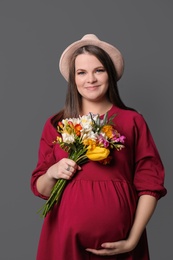 Beautiful pregnant woman with flowers on color background