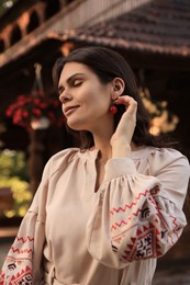 Photo of Beautiful woman wearing embroidered dress in village. Ukrainian national clothes