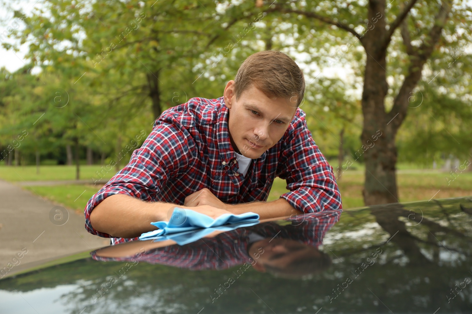 Photo of Man washing car hood with rag outdoors
