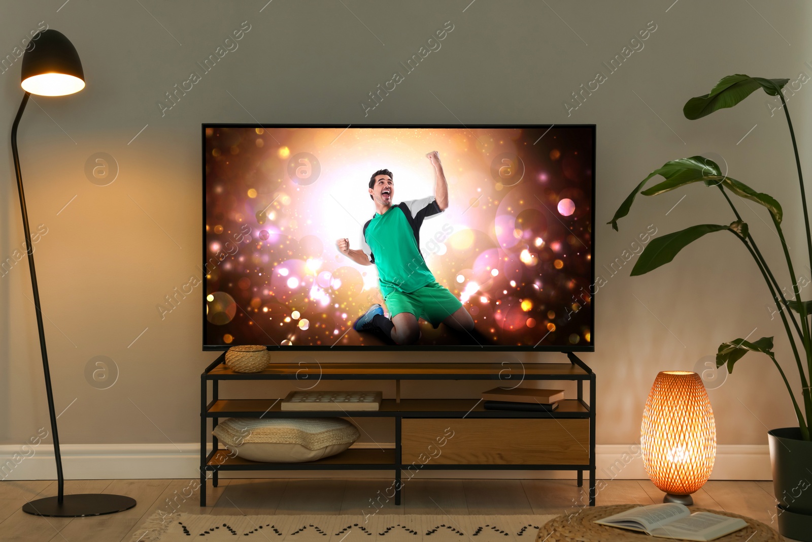Image of Modern TV set on wooden stand in room. Scene of football broadcasting