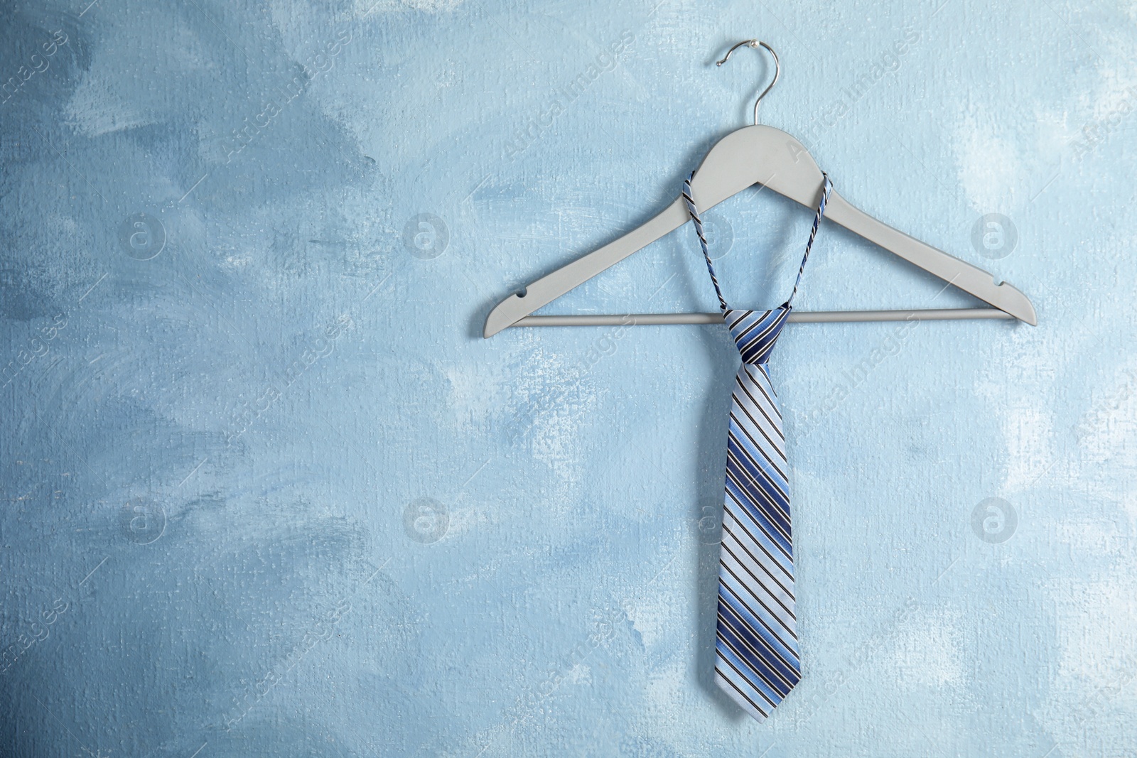 Photo of Tie on wooden hanger against color background. Space for text