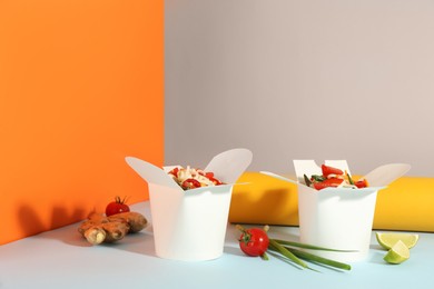 Photo of Boxes of vegetarian wok noodles with ingredients on color background