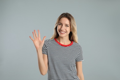 Photo of Woman showing number five with her hand on light grey background