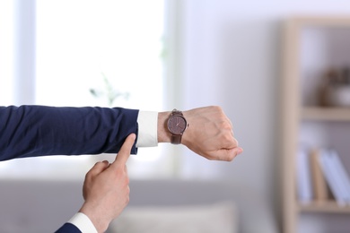 Businessman with wristwatch on blurred background, Time concept