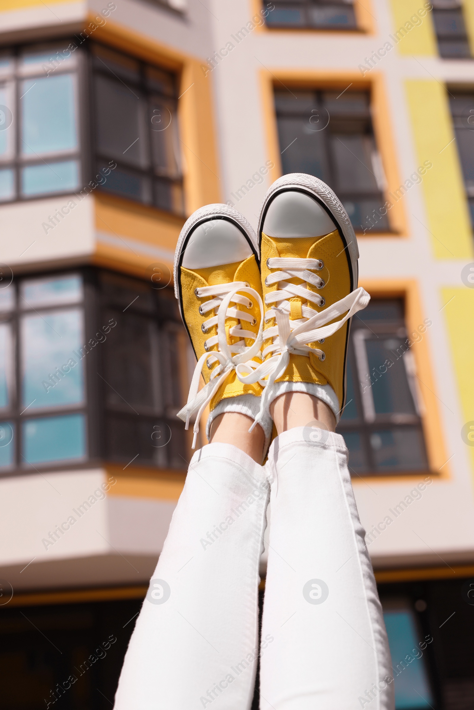 Photo of Woman wearing yellow classic old school sneakers outdoors, closeup