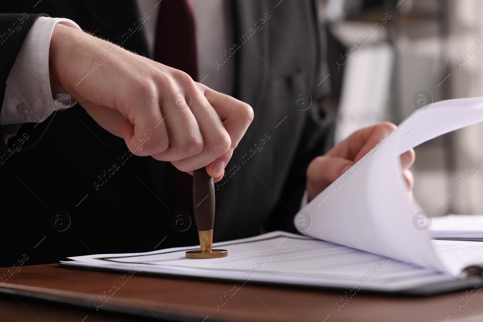 Photo of Notary stamping document at table in office, closeup