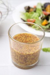 Photo of Tasty vinegar based sauce (Vinaigrette) in glass on light table, closeup